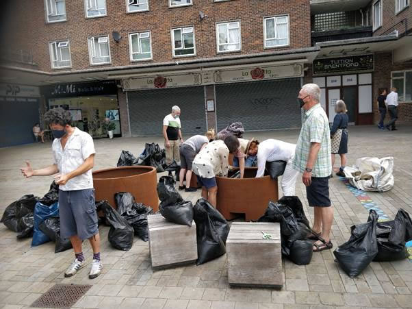 A group of people standing around a bag of luggage Description automatically generated